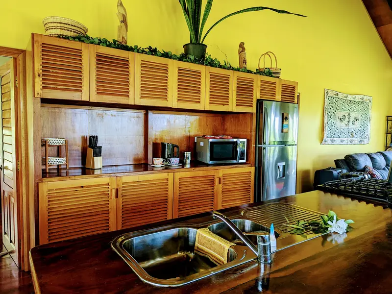 The kitchen with timber cabinets and a sunny yellow wall
